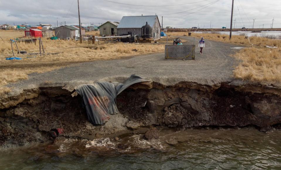 A make-shift barricade blocks a road that has collapsed into water.