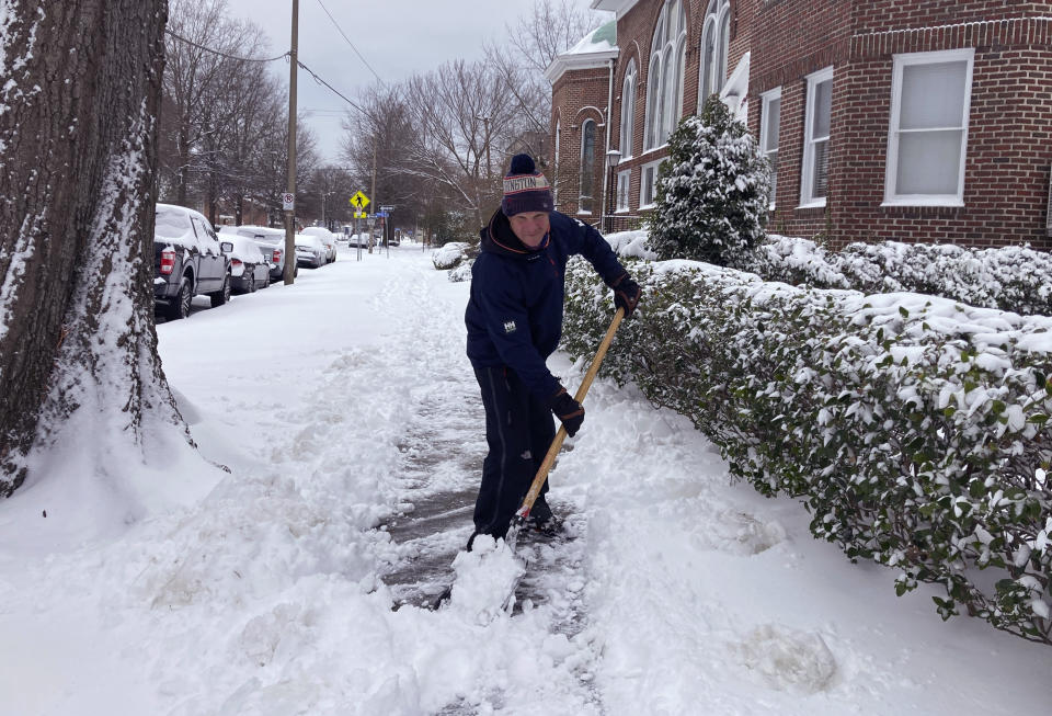 Richard Fuller, 45, shovels a sidewalk in Norfolk, Va., on Saturday Jan. 22, 2022. A winter storm left as much of six inches of snow in parts of coastal Virginia and North Carolina as well as ice further south in parts of North Carolina and South Carolina. (AP Photo/Ben Finley).