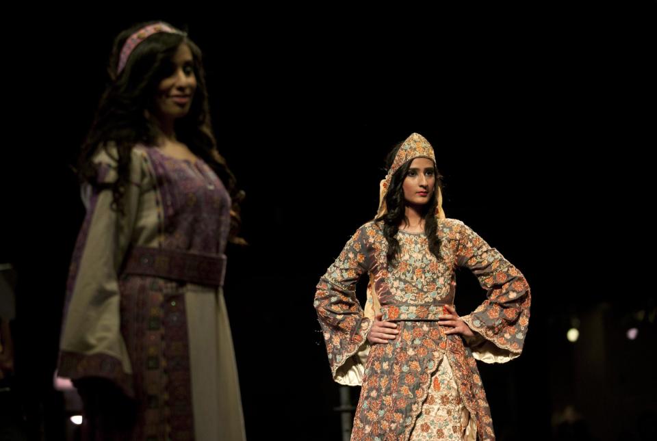 In this photo taken Thursday, May 1, 2014, two models display a blend of traditional Palestinian embroidery and modern designs in a creation by designer Intisar Abdo during the opening day of the Palestine Fashion Week 2014, in the West Bank city of Ramallah. The three-day show, which ended Saturday, May 3, 2014, saw models prowl the catwalk in the only major fashion show in the Palestinian territories. (AP Photo/Nasser Nasser)