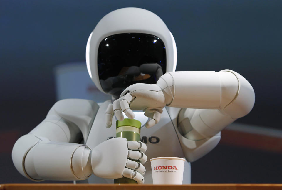 Honda Motor Co's Asimo humanoid robot opens the top of a bottle to pour the drink into a cup during a news conference at the 42nd Tokyo Motor Show in Tokyo November 30, 2011. REUTERS/Toru Hanai (JAPAN - Tags: BUSINESS SCIENCE TECHNOLOGY)