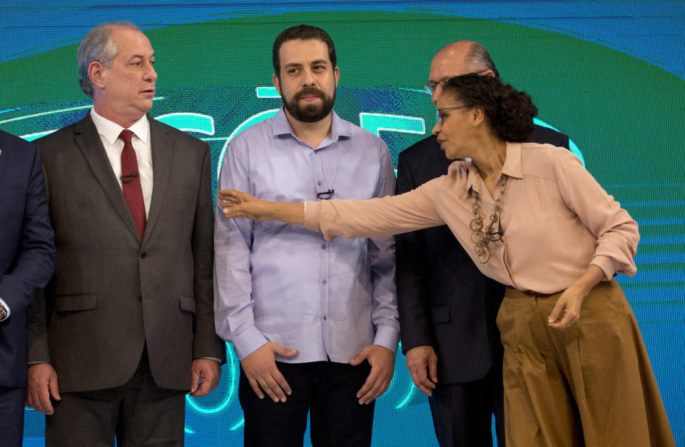 Marina Silva, presidential candidate of the Sustainability Network Party, right, reaches over to speak to Ciro Gomes, presidential candidate of the Democratic Labor Party, left, before the start of a live, televised presidential debate in Rio de Janeiro, Brazil, Thursday, Oct. 4, 2018. Behind are Guilherme Boulos of the Socialism and Liberty Party, center, and Geraldo Alckmin of the Social Democratic Party, behind, right. Brazil will hold general elections on Oct. 7. (AP Photo/Silvia Izquierdo)