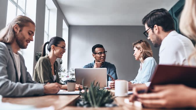 Group of young modern people in smart casual wear discussing business while working in the creative office.