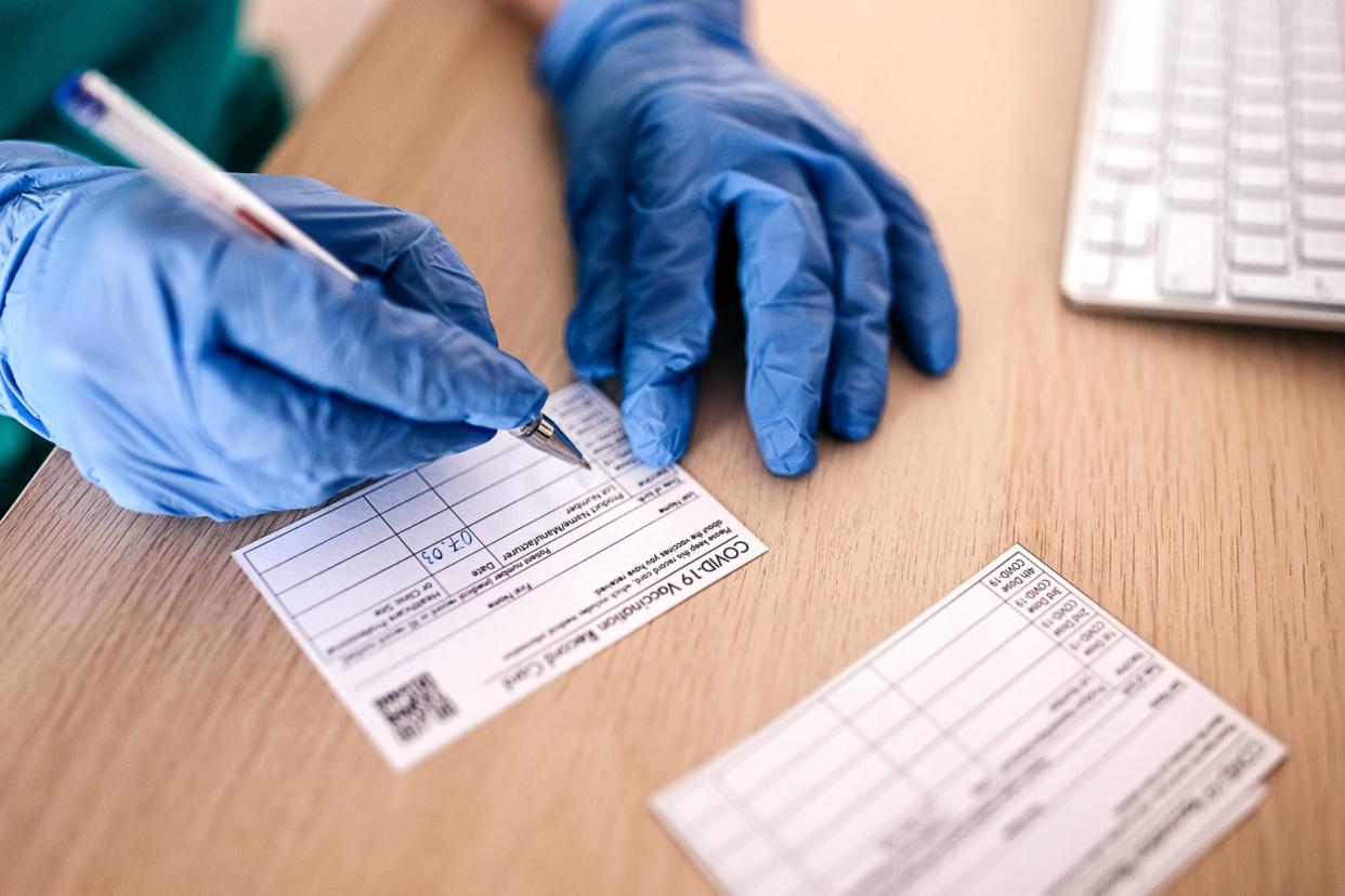 doctor filling in covid-19 vaccine card