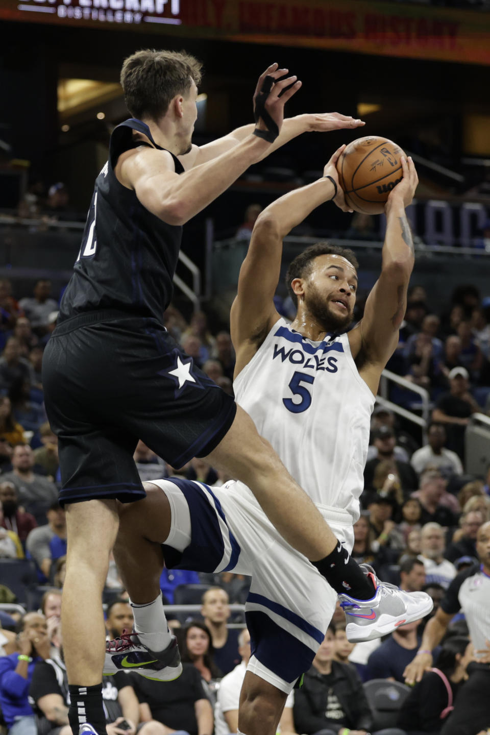 Minnesota Timberwolves guard A.J. Lawson (5) pass the ball as he is defended by Orlando Magic forward Franz Wagner (22) during the first half of an NBA basketball game Wednesday, Nov. 16, 2022, in Orlando, Fla. (AP Photo/Kevin Kolczynski)