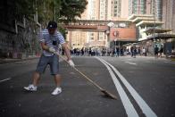 People clear makeshift road barricades placed by protesters outside the University of Hong Kong in Hong Kong