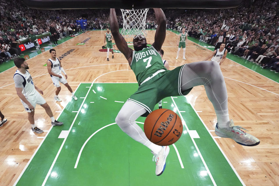 Boston Celtics guard Jaylen Brown (7) hangs on the rim after a dunk during the first half against the Dallas Mavericks in Game 5 of the NBA basketball finals Monday, June 17, 2024, in Boston. (Peter Casey/Pool Photo via AP)