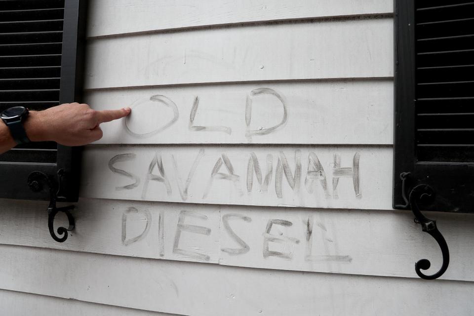 Steve Mott uses his finger to write in the residue on the outside of his home of Washington Square. Mott say's the residue builds up from diesel fumes created by the passing trollies.
