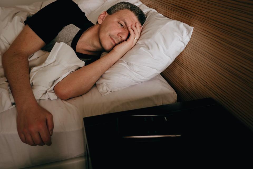 adult man in bed looking at cell phone alarm