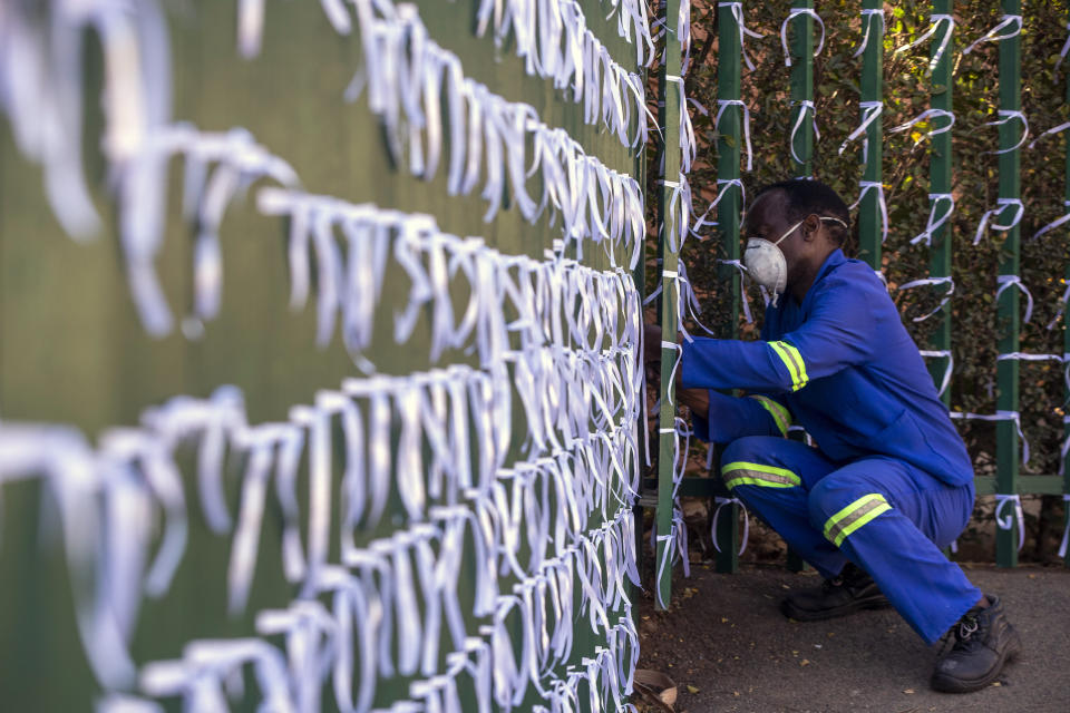 FILE - In this July 29, 2020, file photo, Silva Cossa, the caretaker, ties ribbons onto the fence to represents a South African who has died from COVID-19, at St James Presbyterian church in Bedford Gardens, Johannesburg, South Africa. Africa’s confirmed coronavirus cases have surpassed 1 million, but global health experts tell The Associated Press the true toll is several times higher. Whatever Africa’s real coronavirus toll, the church has quietly been marking the country’s “known” number of deaths by tying white ribbons to its fence. The project's founders say each ribbon really stands for multiple people. (AP Photo/Themba Hadebe, File)