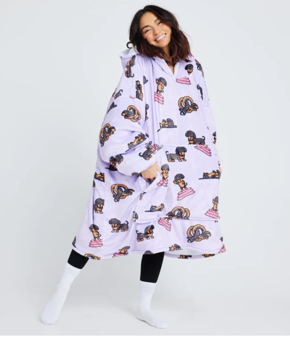 A young woman stands showing off her dachshund themed Oodie