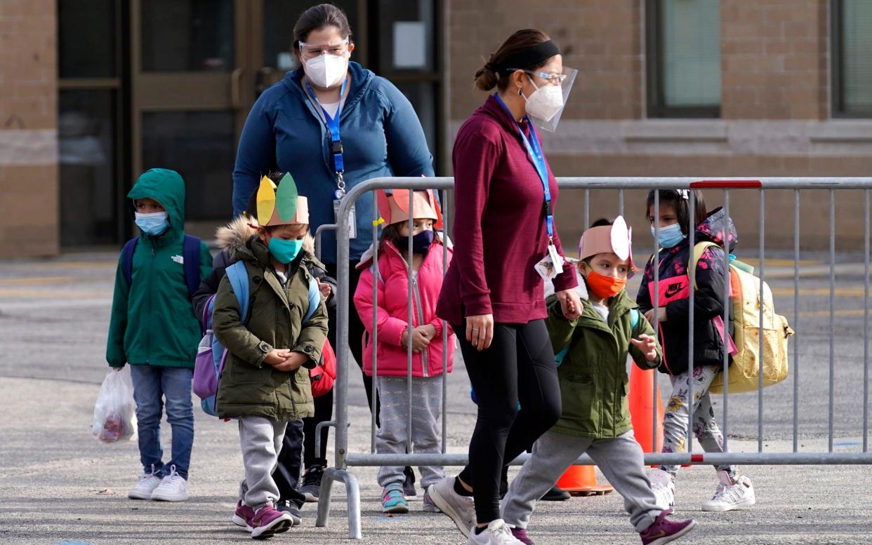 Students walk to a school bus with teachers after in-person classes at school - AP