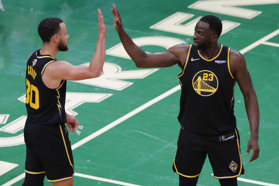 Golden State Warriors guard Stephen Curry (30) and forward Draymond Green (23) high five during the fourth quarter of Game 4 of basketball's NBA Finals against the Boston Celtics, Friday, June 10, 2022, in Boston. (AP Photo/Michael Dwyer)