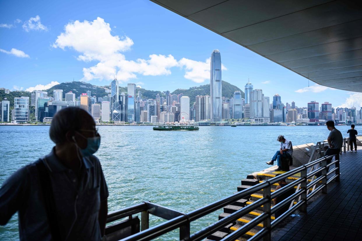 People wear face masks as they visit a promenade on the Kowloon side of Victoria Harbour, which faces the skyline of Hong Kong Island, in Hong Kong on July 13, 2020: AFP via Getty Images