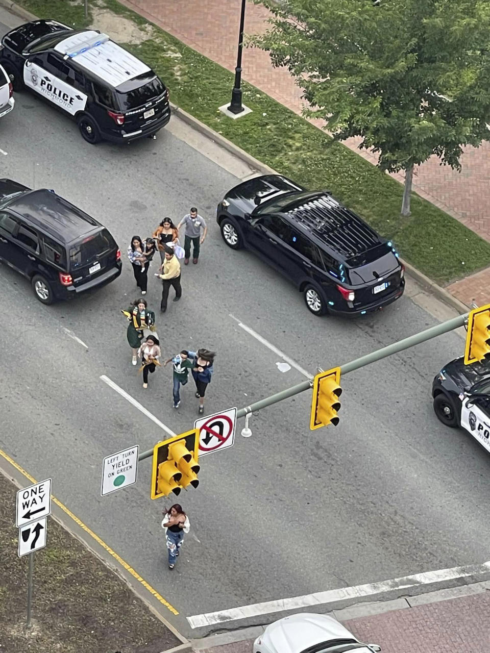 People scatter from a shooting scene as police arrive Tuesday, June 6, 2023, in Richmond, Va. Authorities in Richmond, Virginia, say seven people were shot following a high school graduation ceremony held at a downtown theater near Virginia Commonwealth University. Interim Police Chief Rick Edwards said at a news conference that two suspects were taken into custody after Tuesday's shooting. (John Willard via AP)