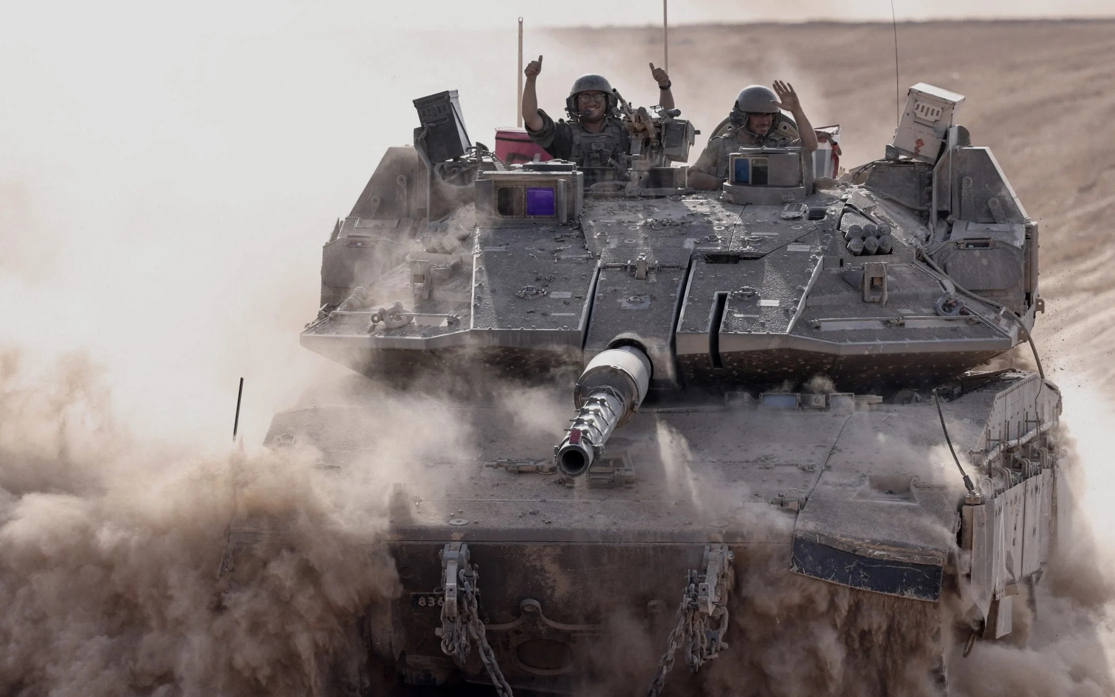 Israeli soldiers gesture from a military vehicle in southern Israel near the border with the Gaza Strip