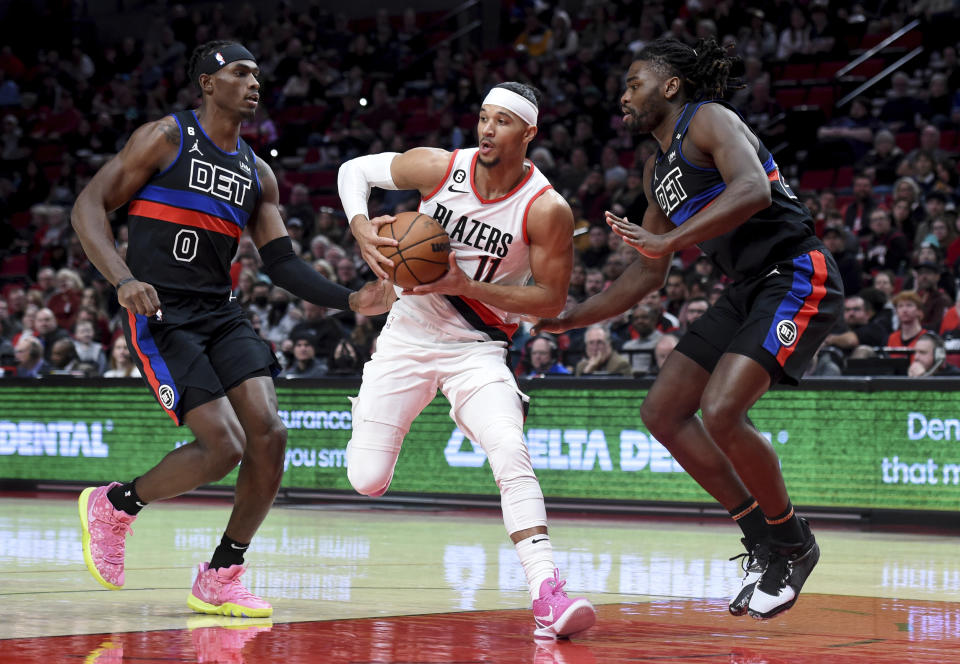Portland Trail Blazers guard Josh Hart, center, drives to the basket against Detroit Pistons centers Jalen Duren, left, and Isaiah Stewart, right, during the first half of an NBA basketball game in Portland, Ore., Monday, Jan. 2, 2023. (AP Photo/Steve Dykes)