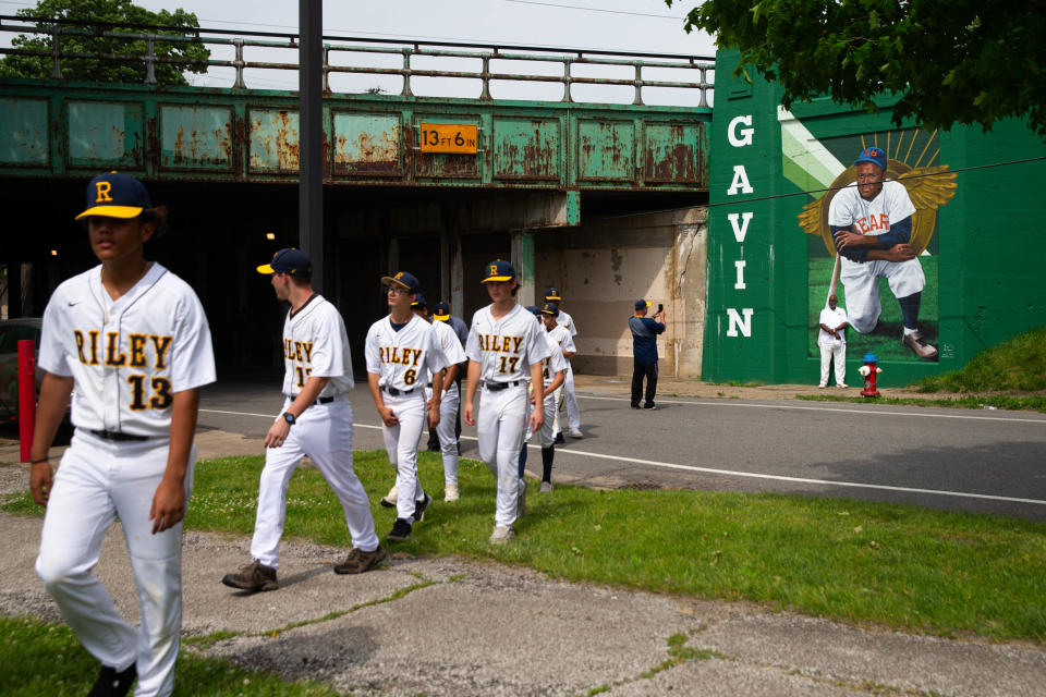 Riley High School athletic director, Seabe Gavin, Jr., gets his photo taken in front of a mural of his father, Seabe Gavin, Sr., during the unveiling of murals at a new public baseball field, Foundry Field, on Monday, May 20, 2024, in South Bend.