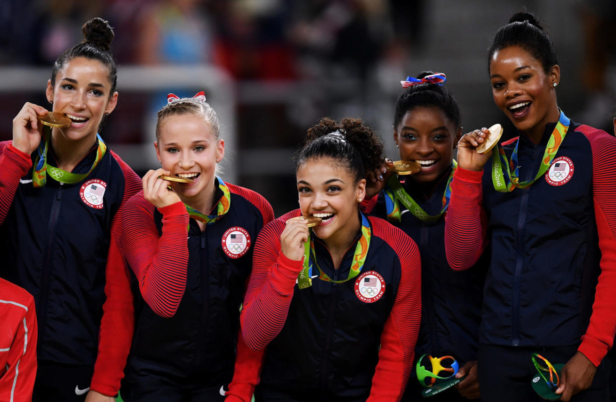 The United States women's olympic gymnastic team biting their gold medals.