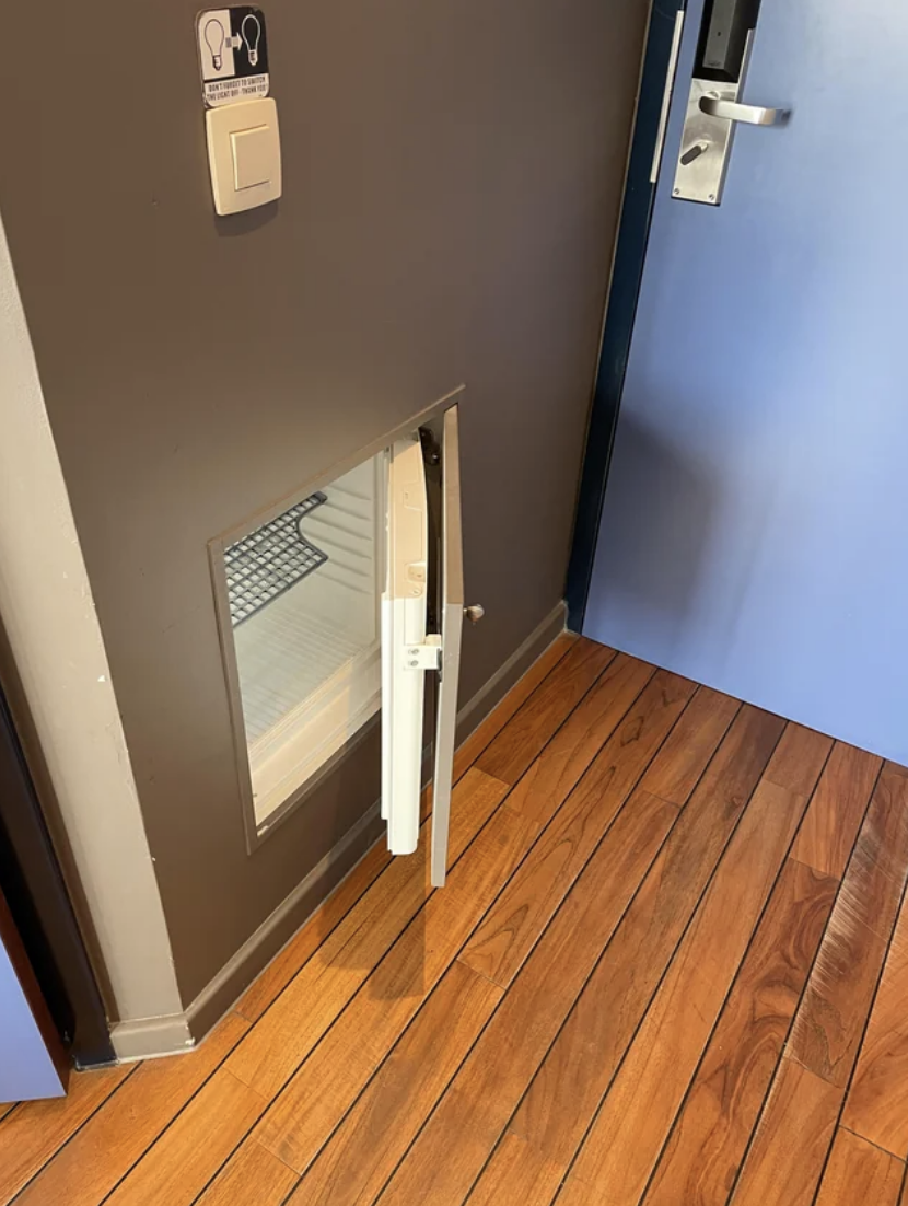 A small pet door is open in a house with a larger door ajar to the right