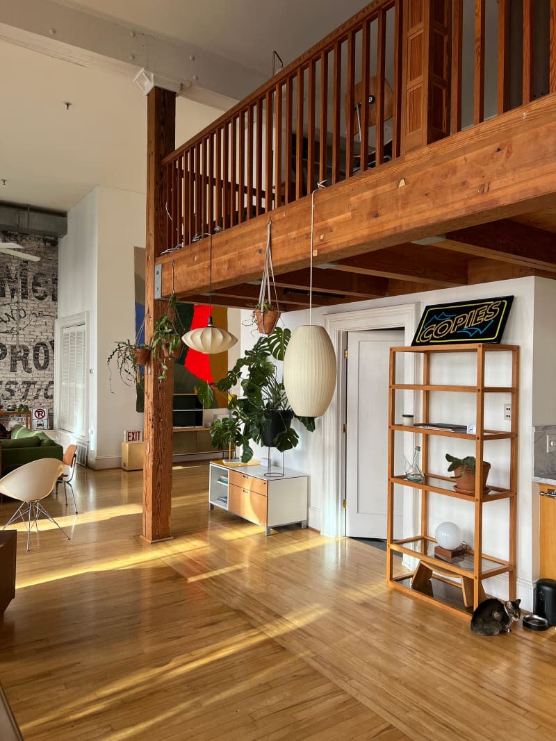 Pendant lights hand in loft with light wood flooring.