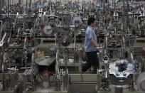 A worker walks past machines on a photo and mirror frame assembly line at a factory in Zibo, Shandong Province May 28, 2012. REUTERS/Aly Song