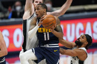 Denver Nuggets guard Monte Morris, front left, drives to the basket past San Antonio Spurs center Jakob Poeltl, back left, and guard Patty Mills in the second half of an NBA basketball game Friday, April 9, 2021, in Denver. (AP Photo/David Zalubowski)