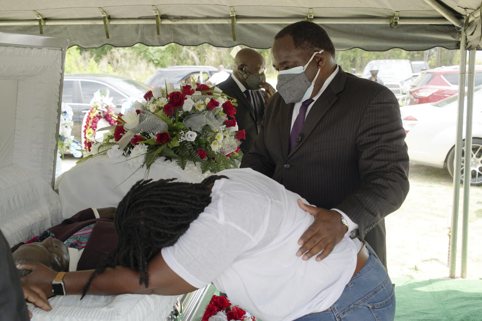 Funeral director Shawn Troy comforts a distraught mourner during a graveside service at Hillcrest Cemetery outside Mullins, S.C., on Monday, May 24, 2021. His father, William Penn Troy Sr., died of COVID-19 in August 2020, one of many Black funeral directors to succumb during the pandemic. (AP Photo/Allen G. Breed)