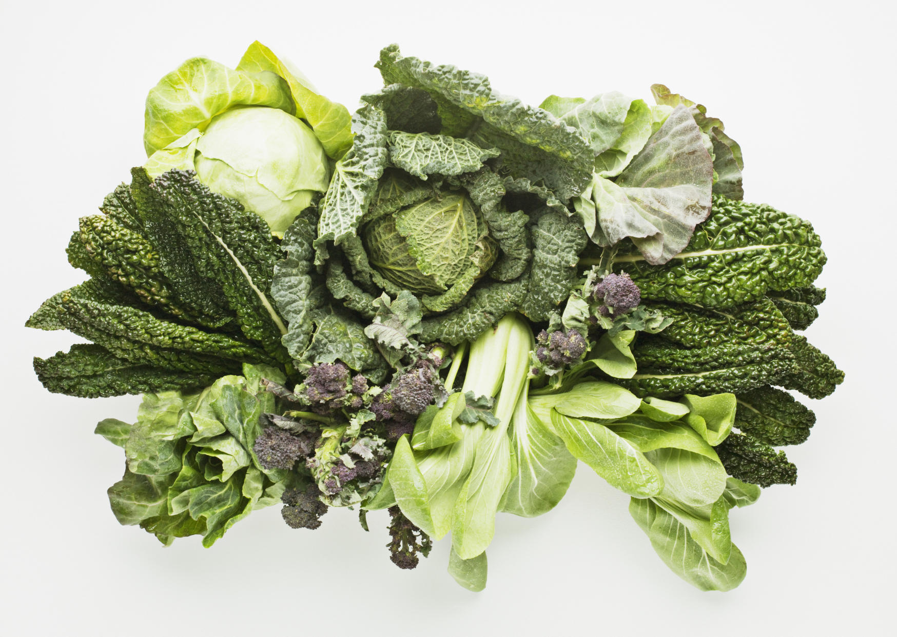 Leafy greens salad, kale, cabbage are seen on a white background. Leafy greens can cause food poisoning.