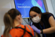 Registered nurse Sofia Mercado, right, administers a vaccine shot at a vaccination event for workers at an Amazon Fulfillment Center, Wednesday, March 31, 2021, in North Las Vegas, Nev. A growing number of companies and labor unions are directly securing coronavirus vaccines for their workers. Amazon and some other large companies have hosted on-site inoculations, while smaller operations have helped book appointments for their workers. (AP Photo/John Locher)