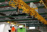 An employee directs an overhead crane used to move large parts around the facility during a media tour of the Boeing 777X at the Boeing Composite Wing Center in Everett