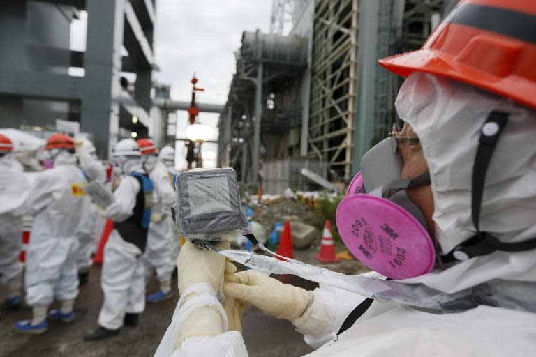 A TEPCO employee measures radiation levels as workers construct an ice wall at the tsunami-crippled Fukushima nuclear power plant in Okuma, Fukushima Prefecture, on July 9, 2014