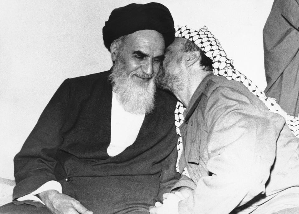 FILE - In this Feb. 18, 1979 file photo, Palestinian Liberation Organization leader Yasser Arafat, right, kisses Ayatollah Ruhollah Khomeini, during a meeting in Tehran, Iran. Monday, Feb. 11, 2019 marks the 40th anniversary of the Islamic Revolution in Iran, which overthrew the caretaker government left behind by the cancer-stricken Shah Mohammad Reza Pahlavi, who had left the country only weeks earlier. (AP Photo, File)