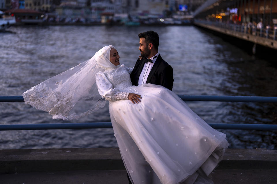 A young couple pose during a photo session at Galata bridge in Istanbul, Turkey, Monday, June 3, 2024. The landmark is a popular location for photograph sessions of couples who are about to or just married. (AP Photo/Francisco Seco)