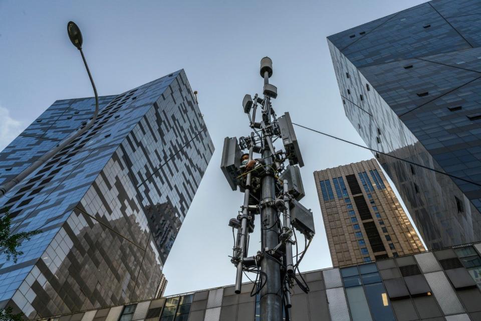 A Chinese technician wears a protective mask as he installs a new Huawei 5G station on a tower in a business district on April 23, 2020 in Beijing, China: Kevin Frayer/Getty Images