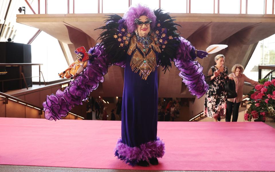 A Dame Edna fan walks down the pink carpet at the service