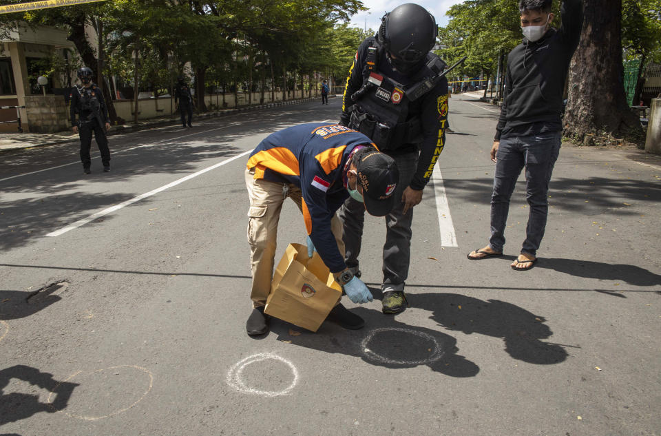 Police officers collect debris near a church where an explosion went off in Makassar, South Sulawesi, Indonesia, Sunday, March 28, 2021. A suicide bomber blew himself up outside a packed Roman Catholic cathedral on Indonesia's Sulawesi island during a Palm Sunday Mass, wounding a number of people, police said. (AP Photo/Yusuf Wahil)