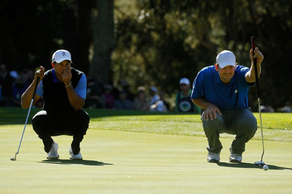 PEBBLE BEACH, CA - FEBRUARY 09: (L-R) Tiger Woods looks on as football player, amateur Tony Romo, lines up his putt on the 11th green during the first round of the AT&T Pebble Beach National Pro-Am at the Spyglass Hill Golf Course on February 9, 2012 in Pebble Beach, California.  (Photo by Jeff Gross/Getty Images)