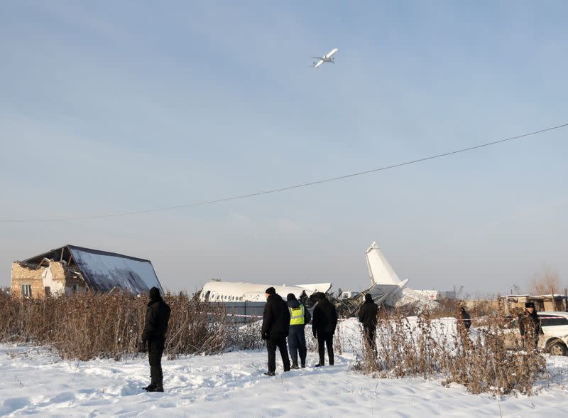 Emergency and security personnel are seen at the site of a plane crash near Almaty