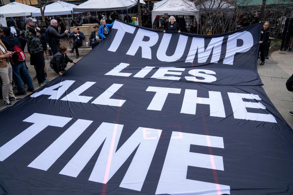 Protesters display a banner criticizing former President Donald Trump outside the Manhattan Criminal Courthouse in New York City on Tuesday.