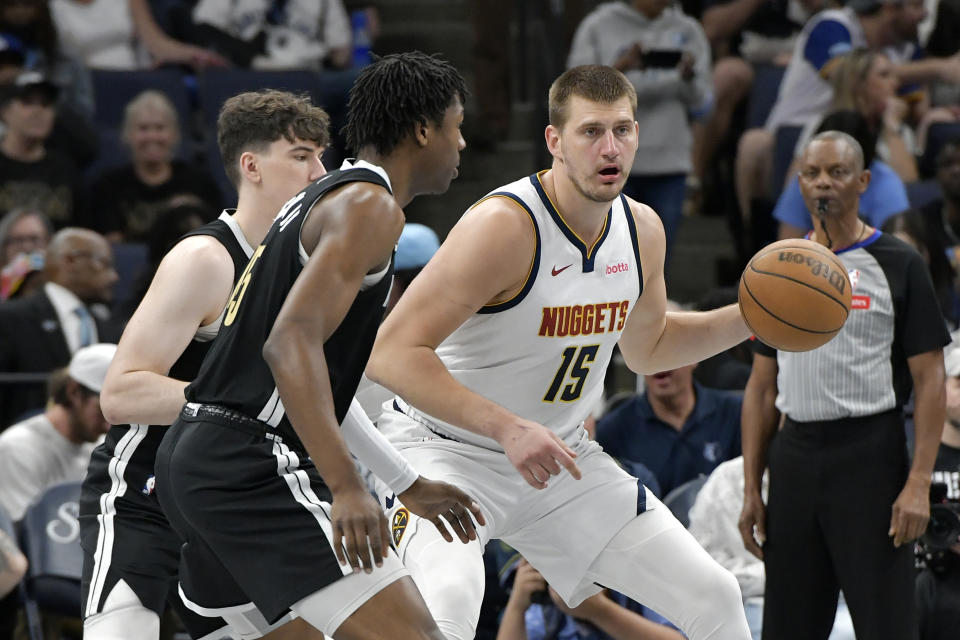 Denver Nuggets center Nikola Jokic (15) handles the ball against Memphis Grizzlies forward GG Jackson, front left, in the first half of an NBA basketball game Sunday, April 14, 2024, in Memphis, Tenn. (AP Photo/Brandon Dill)