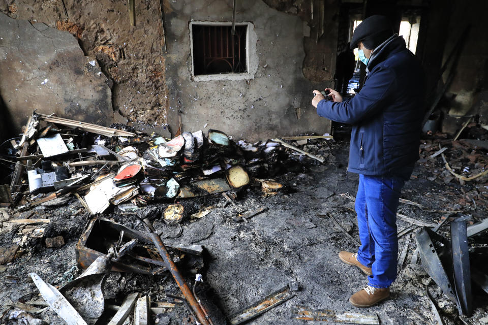 A man takes pictures by his mobile phone for burned documents inside a damaged office of Tripoli municipality that was set on fire by protesters Thursday night, during a protest against deteriorating living conditions and strict coronavirus lockdown measures, in Tripoli, Lebanon, Friday, Jan. 29, 2021. (AP Photo/Hussein Malla)