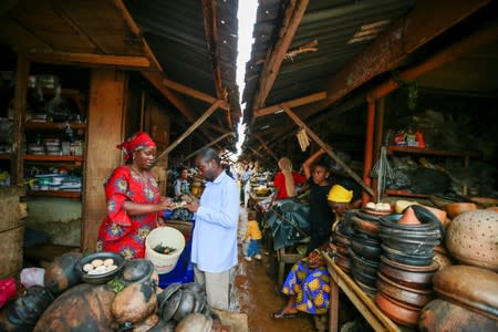 Agbetuya Samuel, a local traditional healer and trader, is seen negotiating the price of pangolin head with a woman who trades herbal materials at a market in Akure, Ondo