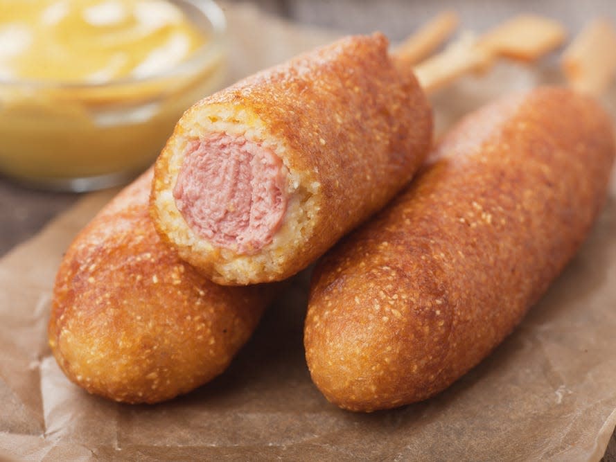 corn dogs on a plate with bite taken out of one of them