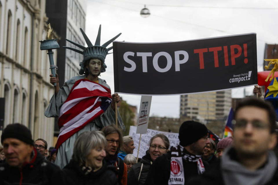 A man on stilts dressed like the Statue of Liberty walks in front of balloons forming the slogan “Stop TTIP” during a protest of thousands of demonstrators against the planned Transatlantic Trade and Investment Partnership (TTIP) and the Comprehensive Economic and Trade Agreement (CETA) ahead of a visit by President Obama in Hanover, Germany, April 23, 2016. (Markus Schreiber/AP)