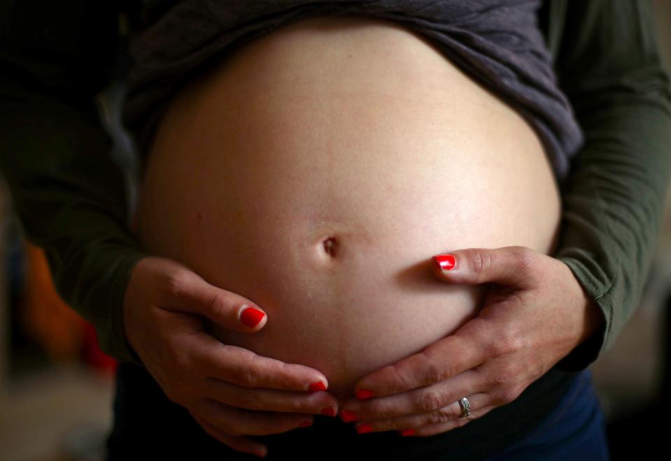 A pregnant woman holds her stomach (PA Archive)