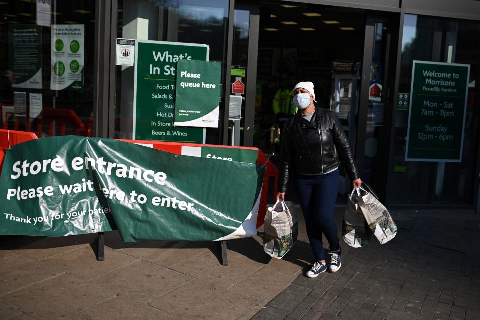 A shoppers wears a mask as he carries his groceries out of a supermarket in Manchester, north west England on March 27, 2020. - Britain was under lockdown, its population joining around 1.7 billion people around the globe ordered to stay indoors to curb the "accelerating" spread of the coronavirus. (Photo by Oli SCARFF / AFP) (Photo by OLI SCARFF/AFP via Getty Images)