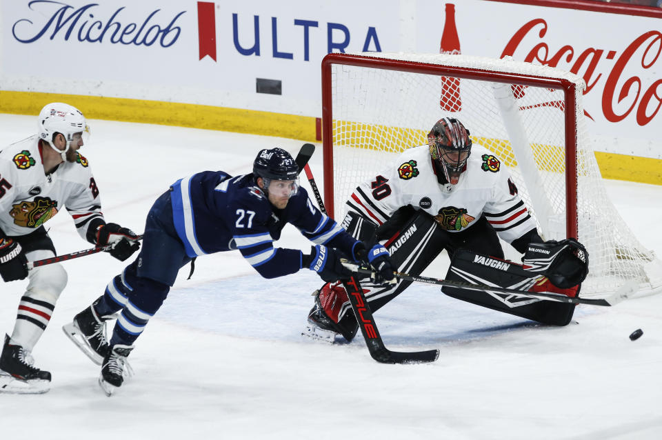 Winnipeg Jets' Nikolaj Ehlers (27) attempts to tip the puck past Chicago Blackhawks goaltender Arvid Soderblom (40) as Jarred Tinordi (25) defends during the second period of an NHL game in Winnipeg, Manitoba, Saturday, Dec. 2, 2023. (John Woods/The Canadian Press via AP)