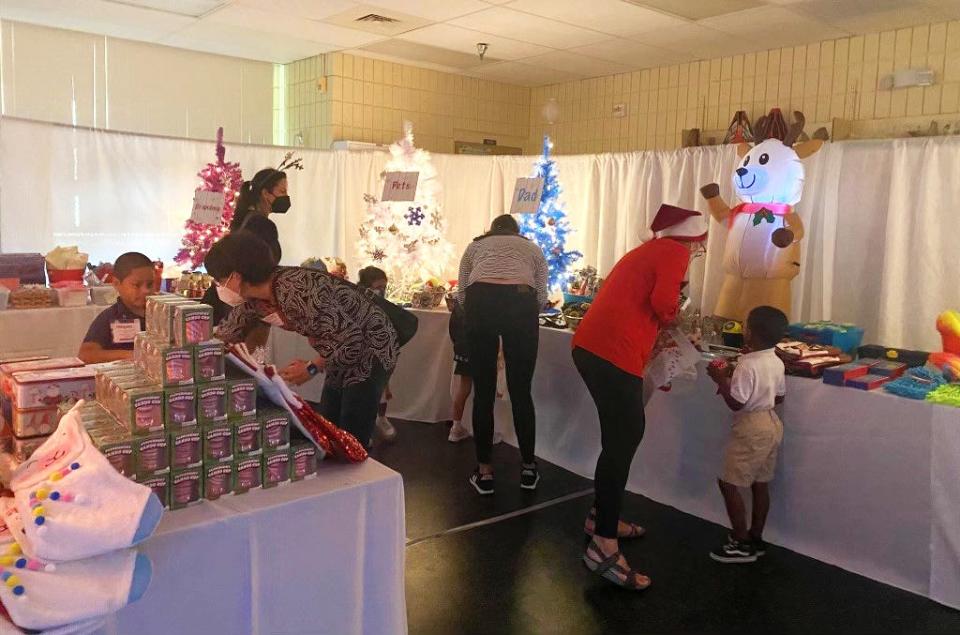 Students at Booker Elementary School shop with volunteers at the 2021 Holiday House last year.