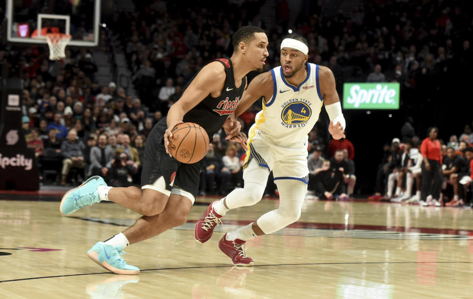 Portland Trail Blazers guard Malcolm Brogdon, left, drives to the basket against Golden State Warriors guard Moses Moody, right, during the first half of an NBA basketball game in Portland, Ore., Sunday, Dec. 17, 2023. (AP Photo/Steve Dykes)
