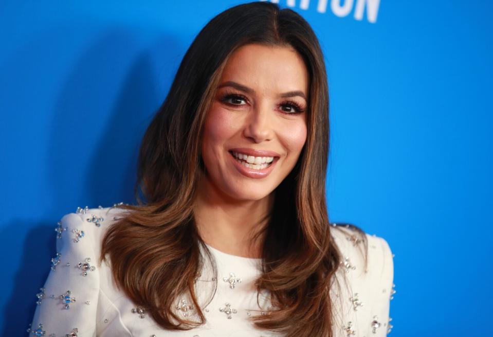 Eva Longoria smiles in front of a blue background